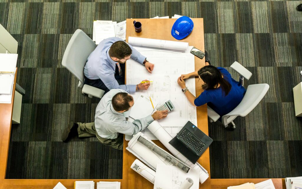 Architects and engineers collaborating on building plans at office desk